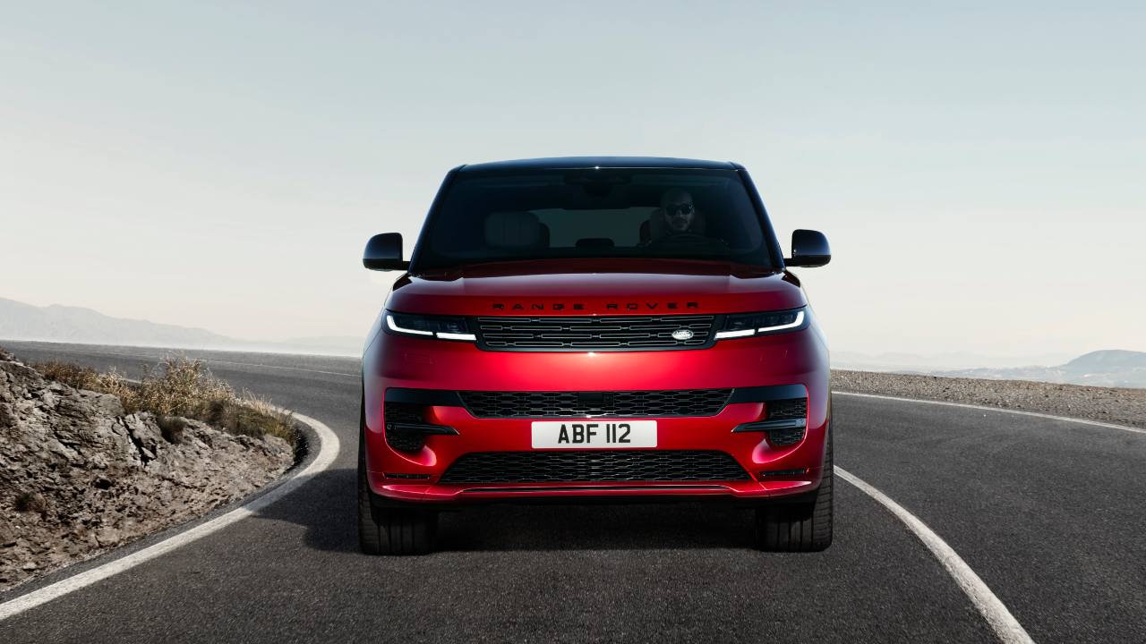 Red Range Rover Sport driving on a winding mountain road from a front view