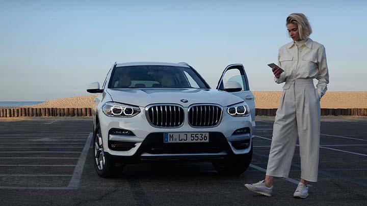 woman standing in front of bmw x1 using my bmw app