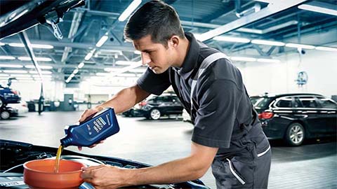technician refilling engine oil on bmw
