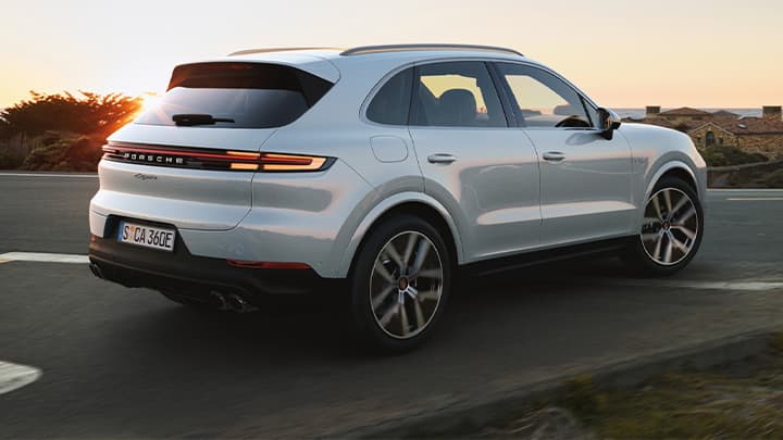 White Porsche Cayenne leaving a junction with a sunset background